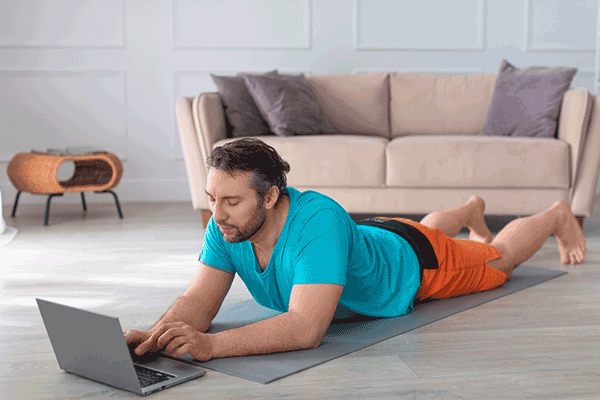 video lower back pain recovery course man lying on floor looking at laptop