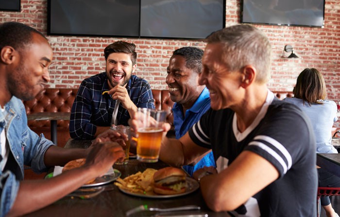 group of middle aged men eating and drinking and having a good time 