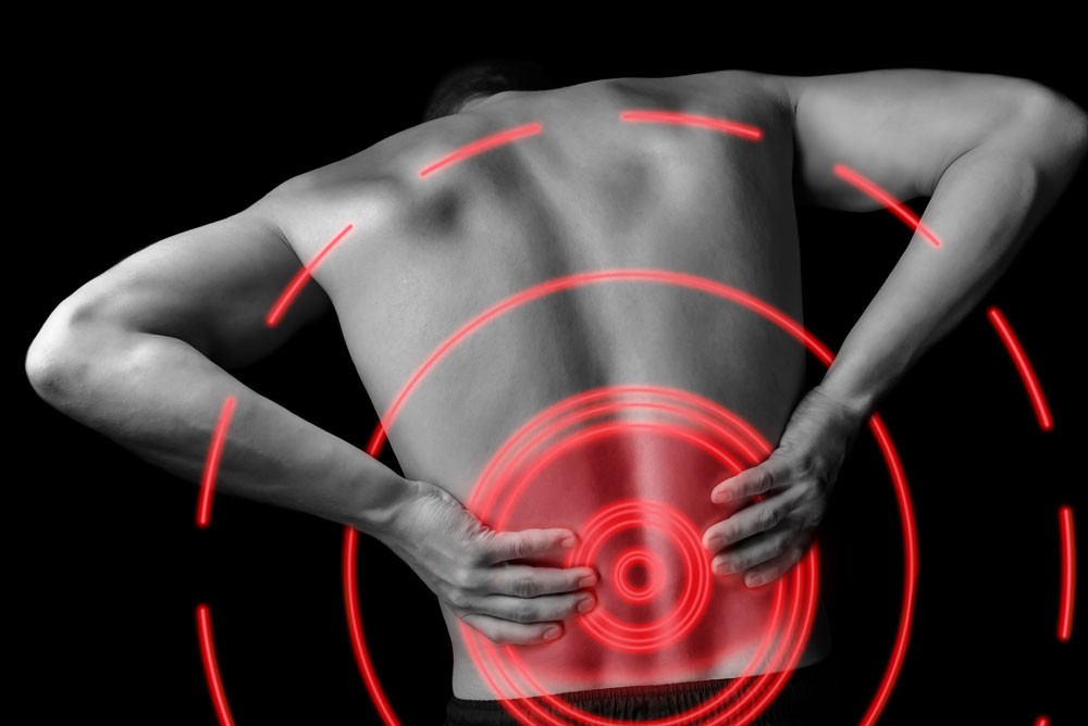 man with lower back pain holding his lower back