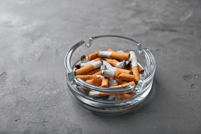an ashtray filled with cigarettes and the influence of nicotine on lower back pain