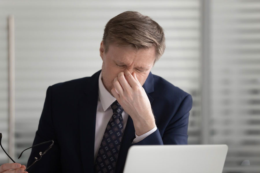 middle aged man with eye strain in front of laptop