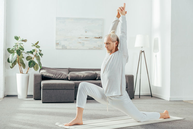 middle aged man doing yoga as exercise in his living room