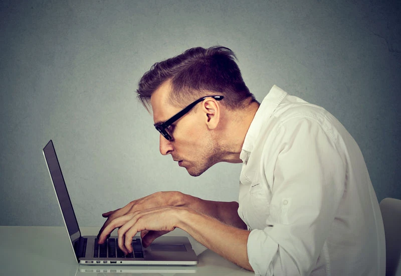 man working on laptop with hunched over posture