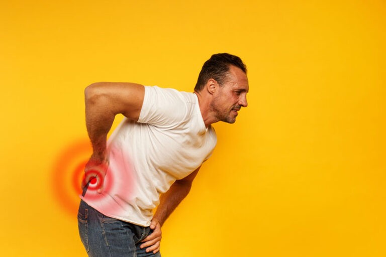 man bent over holding lower back with chronic lower back pain
