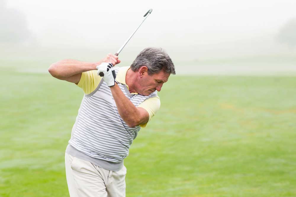 middle aged man playing golf with lower back pain