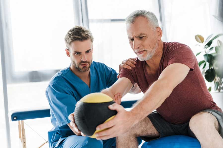 older man on physio ball performing lower back rehabilitation