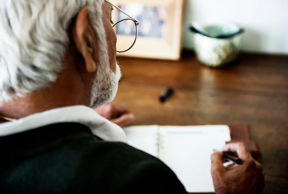 old man journaling his pain triggers to help his chronic back pain