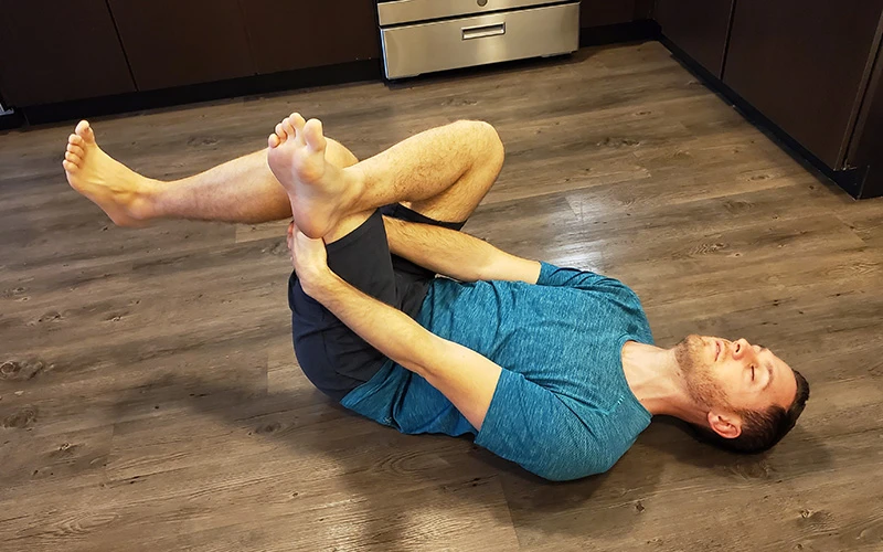 man on his back doing a glute stretch to help with his sciatica pain