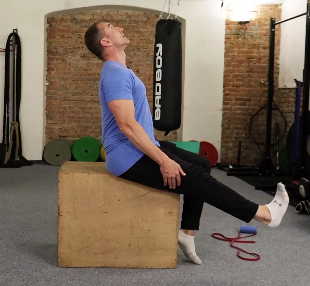 man sitting on a box performing a sciatica nerve glide