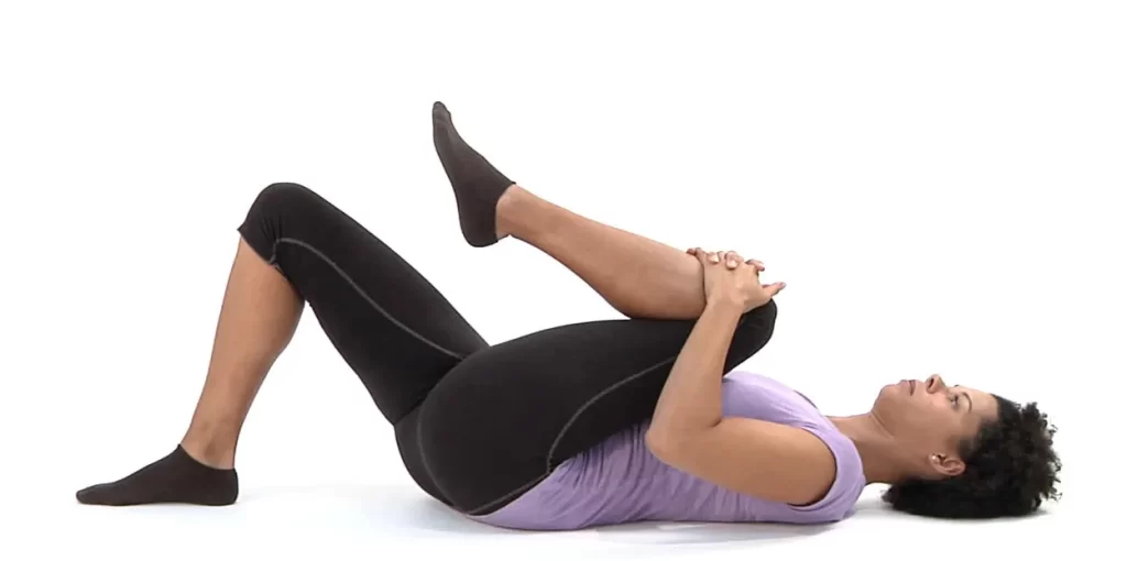 lady on her back pulling one knee to her shoulder for sciatica pain relief